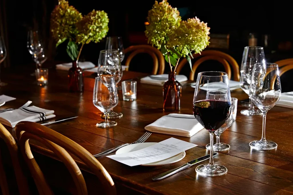 Upscale restaurant dining table with place settings, wine, hydrangeas, and candles.