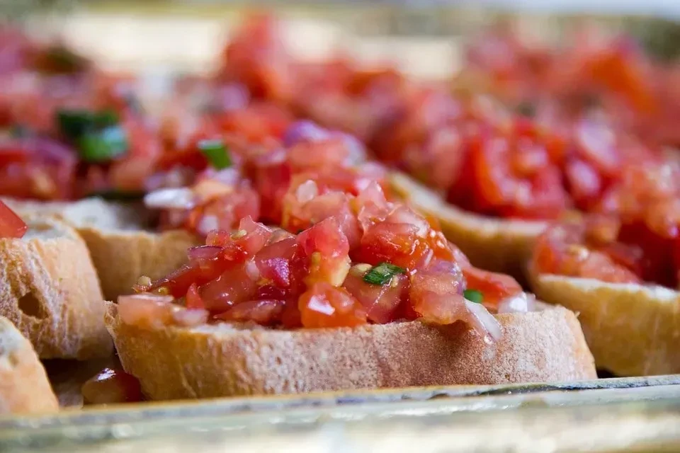 Close-up of bruschetta topped with fresh diced tomatoes and green herbs.