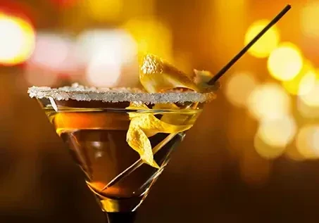 Amber cocktail in martini glass with sugar rim and citrus peel.