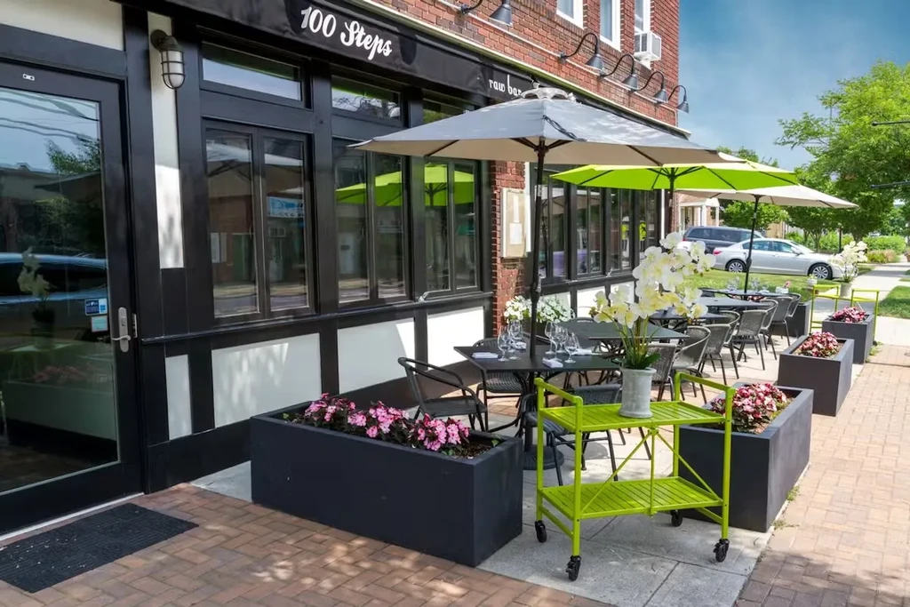 Outdoor dining patio with tables, chairs, and umbrellas in front of a restaurant.