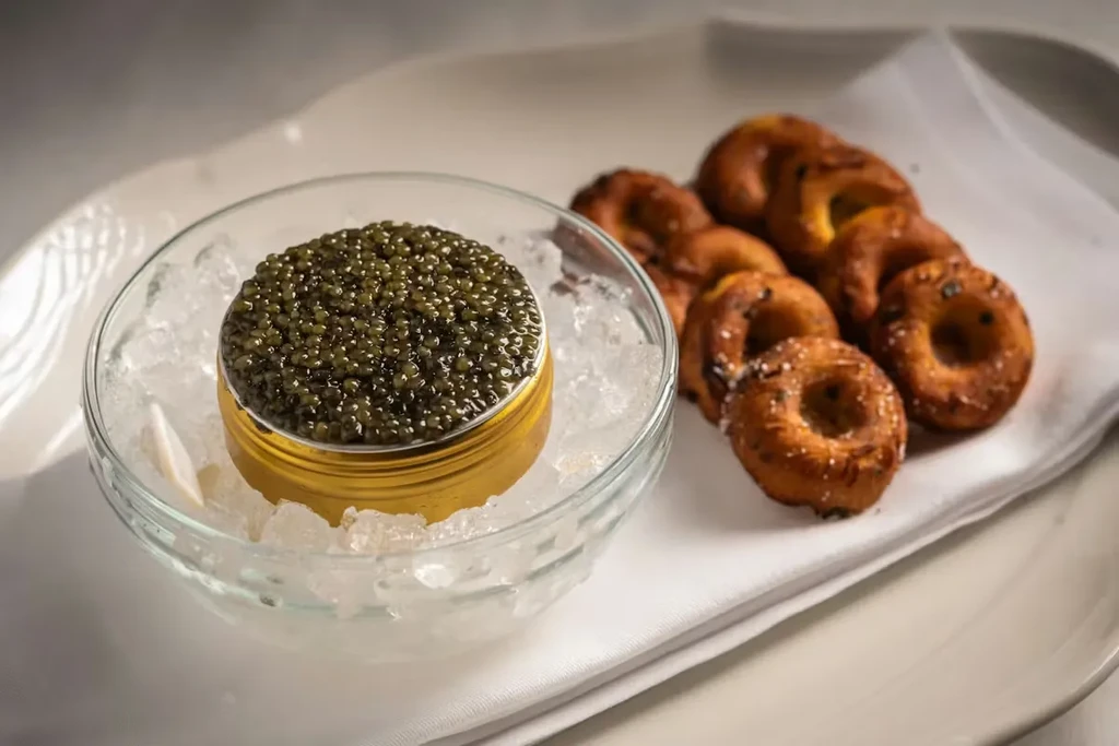 Golden caviar tin on crushed ice, with small baked goods.