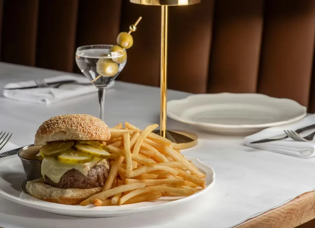 Gourmet burger, golden fries, and olive martini in a restaurant.