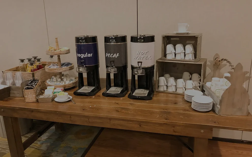 Organized beverage station with coffee, hot water, tea, juices, and mugs.