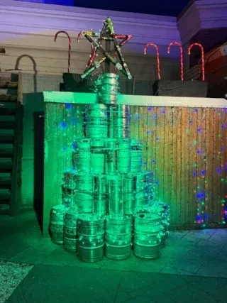 A Christmas tree made of green-lit beer kegs, topped with a star.