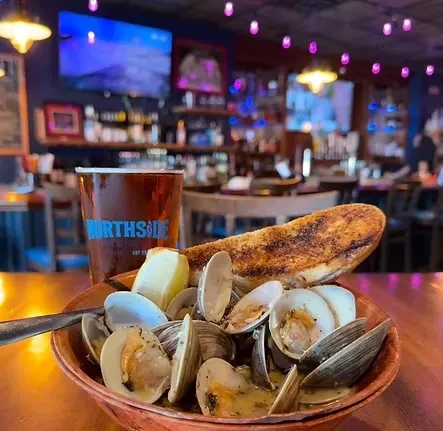 Steamed clams with lemon and bread, pint of beer in a bar.