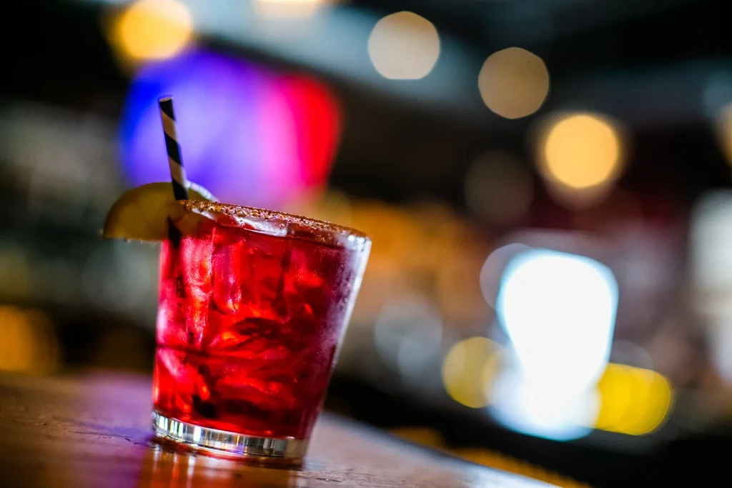 Frosty red cocktail with lime, straw, and sugared rim.