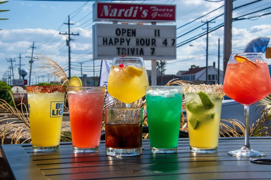 Six colorful drinks on an outdoor table at Nardi's Tavern.