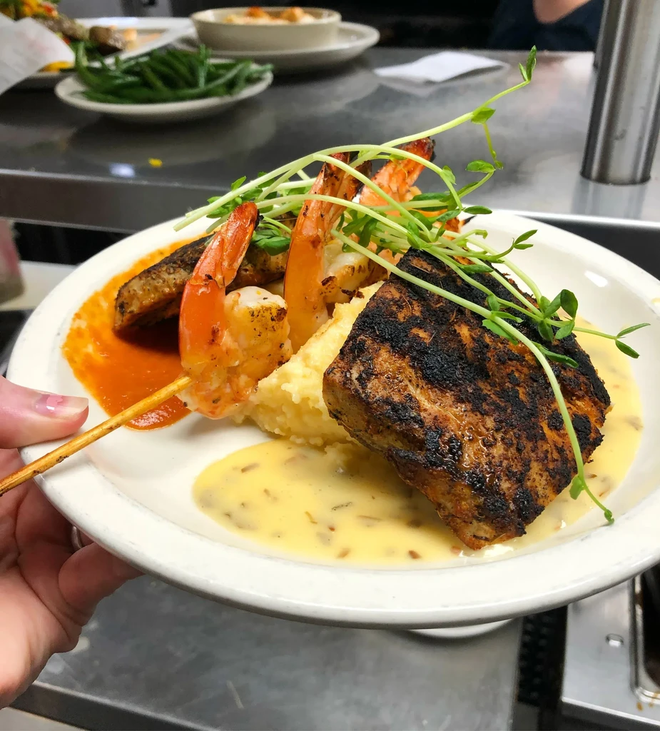 Grilled fish and shrimp plate with purée, sauces, and sprouts.