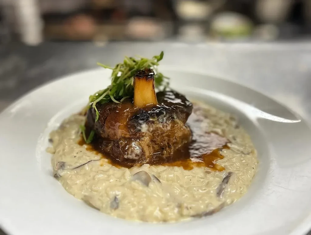 Braised bone-in meat, glossy sauce, microgreens, on mushroom risotto.