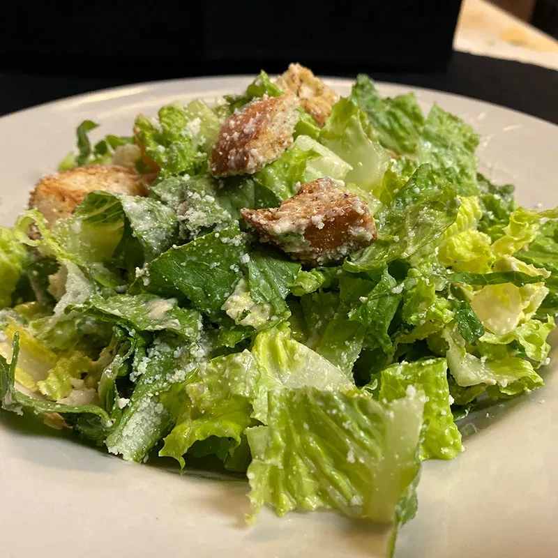 Close-up of Caesar salad with romaine, croutons, and Parmesan cheese.