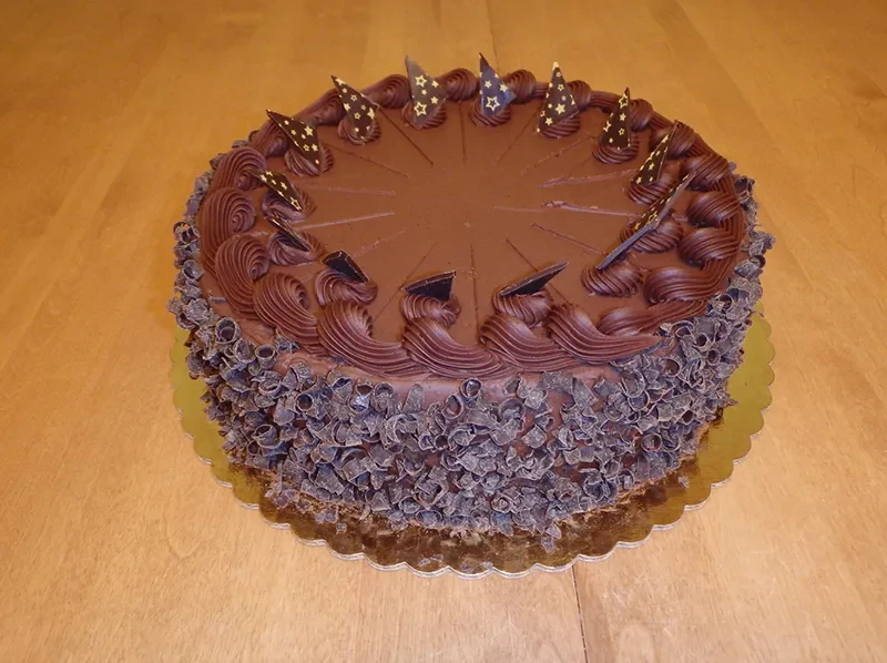 Dark chocolate cake with intricate piping, star pieces, and curls.