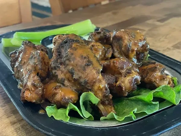 Platter of sauced chicken wings, celery, and white dipping sauce.