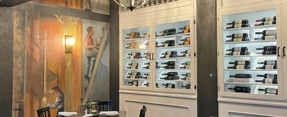 Restaurant featuring bright LED-lit wine cabinets and a rustic mural.