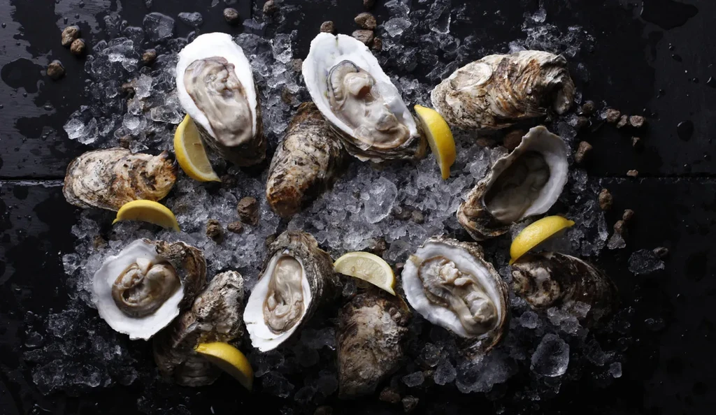 Shucked and unshucked oysters on crushed ice with lemon wedges.