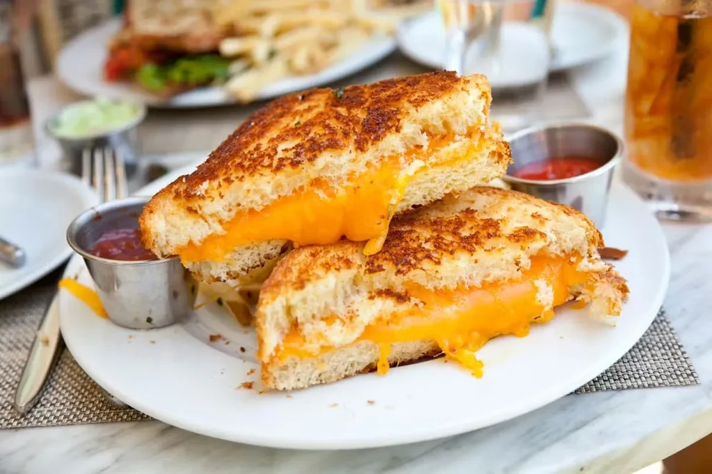 Golden grilled cheese sandwich halves with red and green dipping sauces.