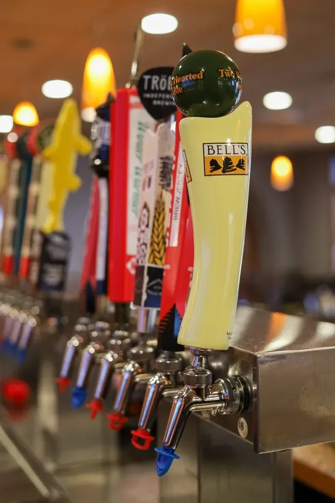 Close-up of distinct beer tap handles and colorful spigots at a bar.
