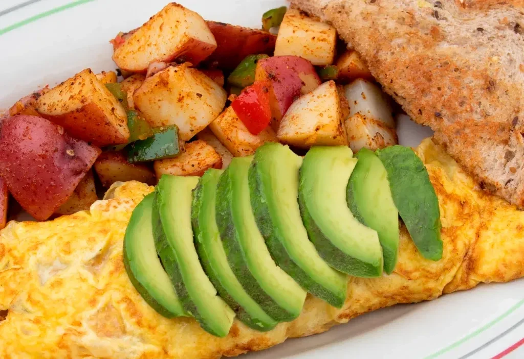 Fluffy golden omelet, avocado, roasted potatoes, and whole-grain toast.