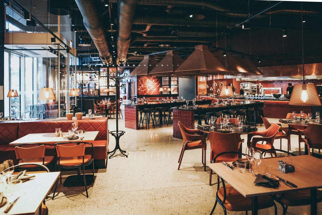 Industrial-style restaurant with red booths and copper kitchen hoods.