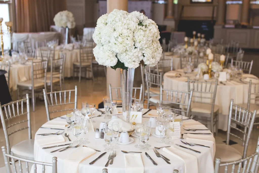 Elegant dining table with white hydrangea centerpiece, Chiavari chairs, and table '11'.