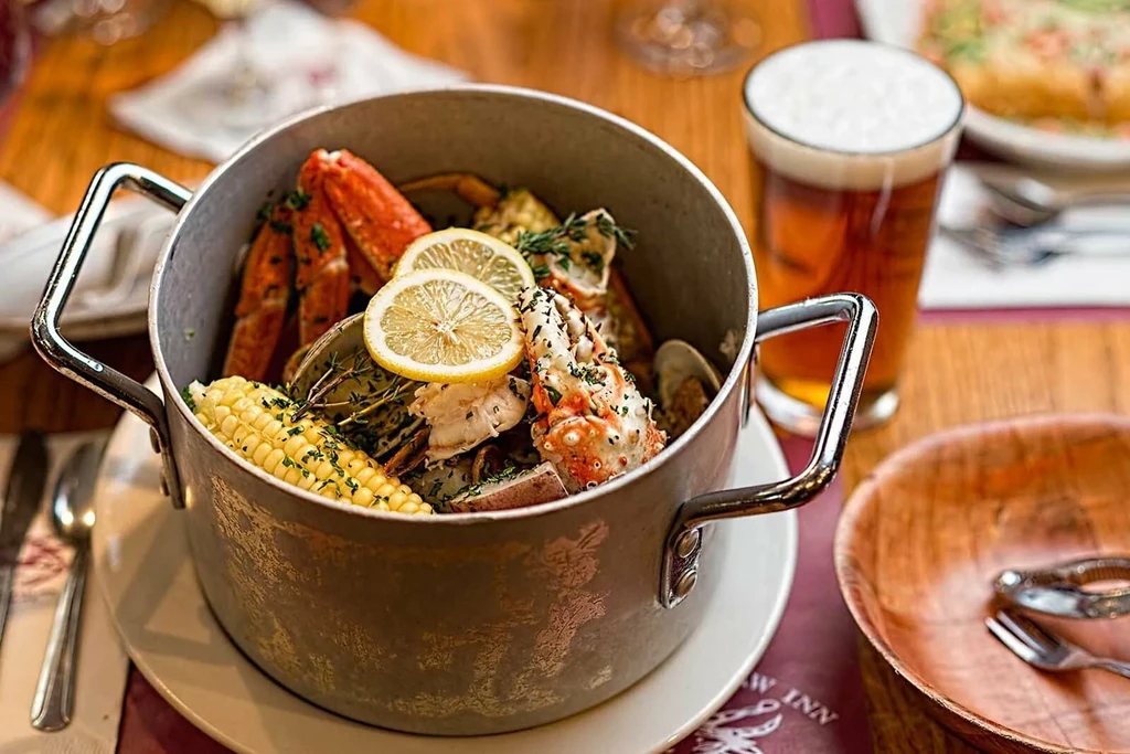 Close-up of metal pot overflowing with vibrant seafood boil and beer.