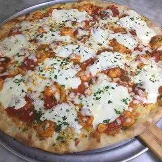 Round pizza with cooked shrimp, melted mozzarella, and green herbs.
