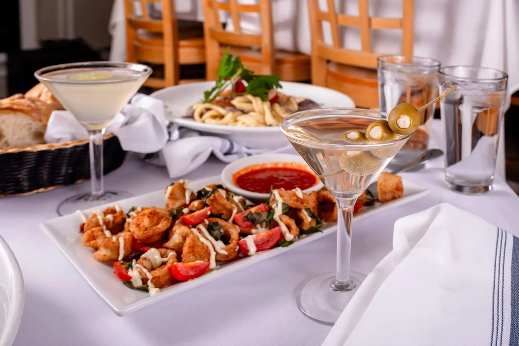 Fried calamari, pasta, bread, and martinis on a restaurant table.