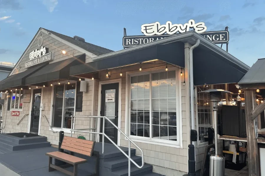 Ebby's Ristorante & Lounge exterior with dark awnings, string lights, and patio.