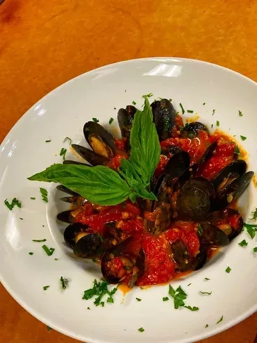 Mussels in rich red tomato sauce, with green basil and parsley.