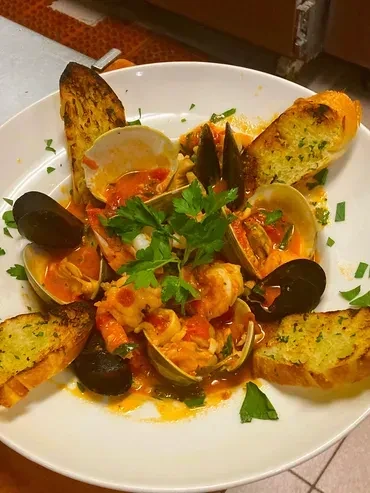 Seafood dish with clams, mussels, shrimp, parsley, and toasted bread.