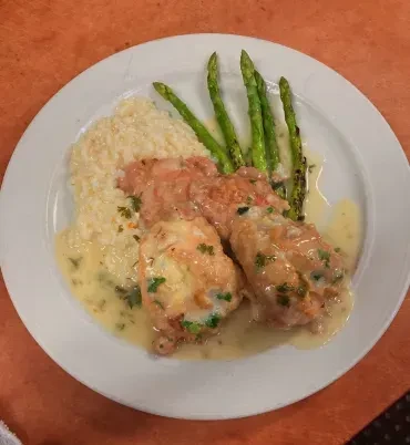 Plated meal: protein with creamy herb sauce, risotto, and asparagus.