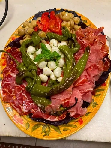 Large ornate platter of cured meats, mozzarella, and roasted vegetables.