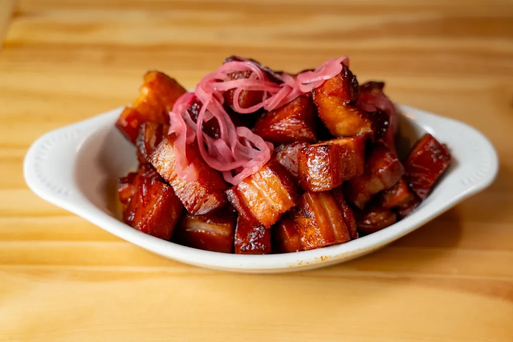 Diced meat in dark glossy sauce, topped with pink pickled onions.