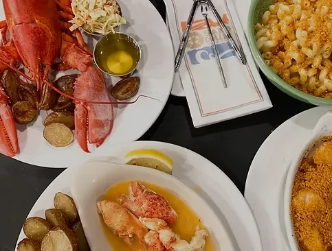 Top-down view of whole lobster, picked lobster, mac and cheese, potatoes.