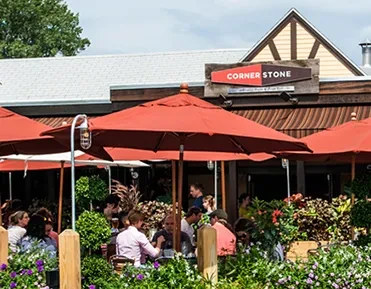 CORNER STONE restaurant's vibrant outdoor patio with red umbrellas and diners.