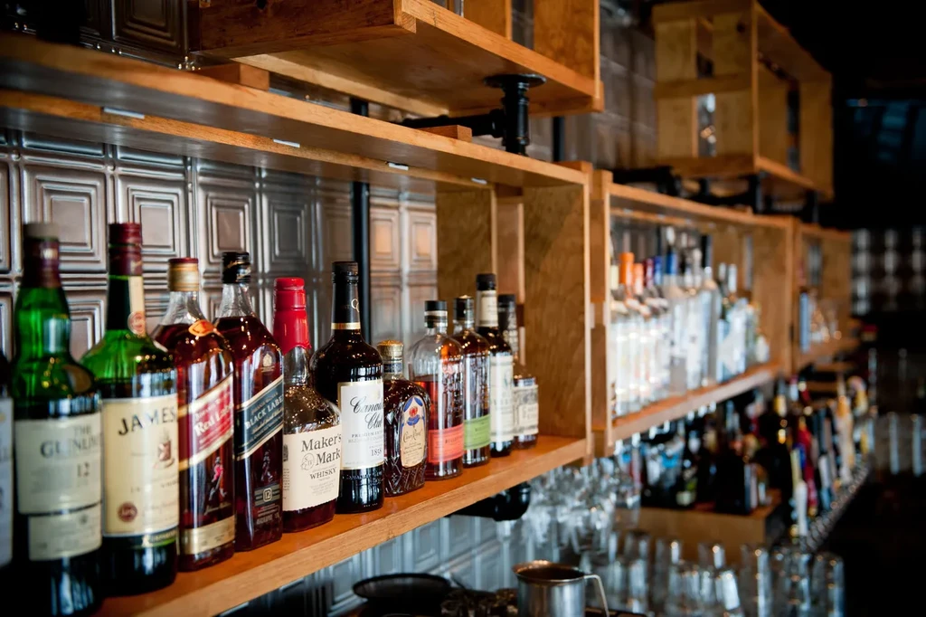 Well-stocked bar shelf displaying numerous branded spirit bottles.