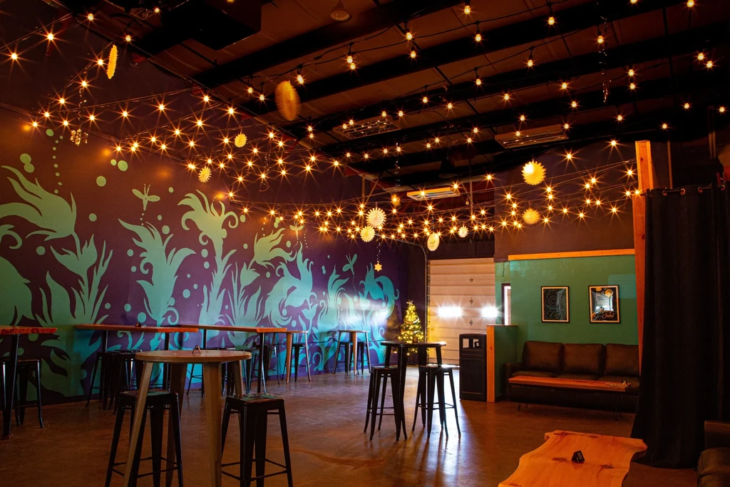 Cozy, dimly lit restaurant interior with fairy lights and a plant mural.