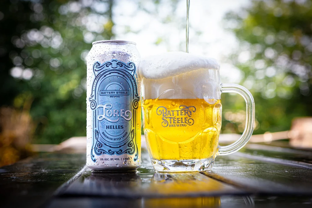 Cold Helles lager can filling branded beer mug outdoors.