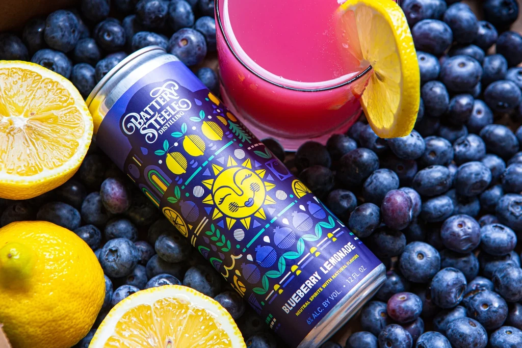 Can of Battery Steele Blueberry Lemonade, glass, fresh blueberries, and lemons.
