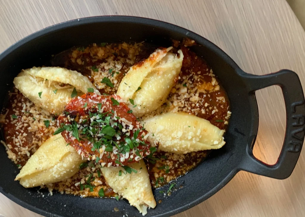 Five stuffed pasta shells in tomato sauce, cheese, and herbs.
