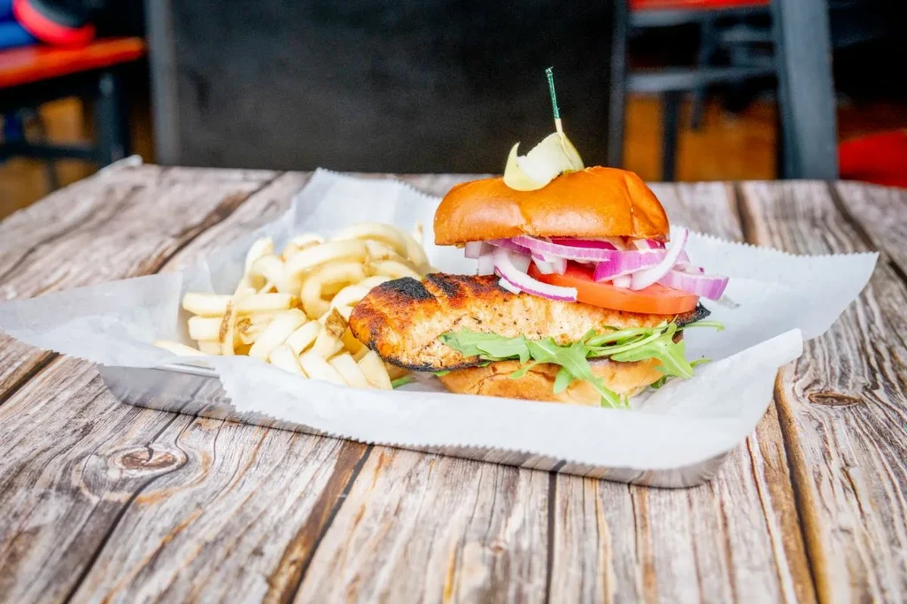 Grilled fish/chicken sandwich with arugula, tomato, onion, and curly fries.