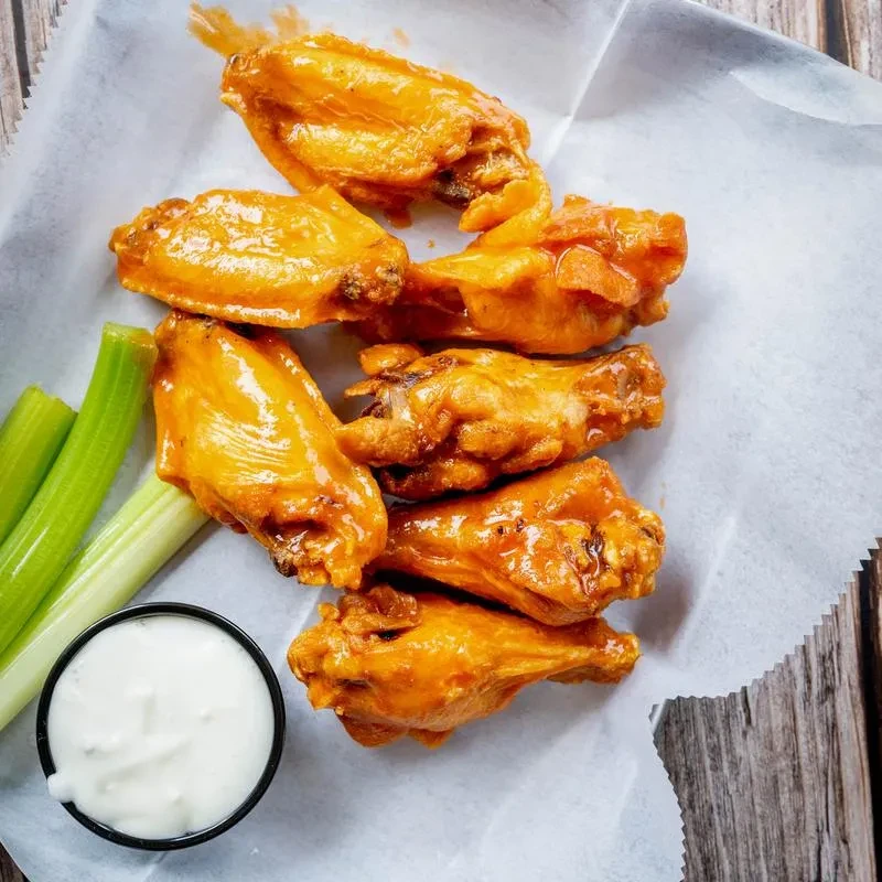 Close-up of buffalo chicken wings with celery and dipping sauce.