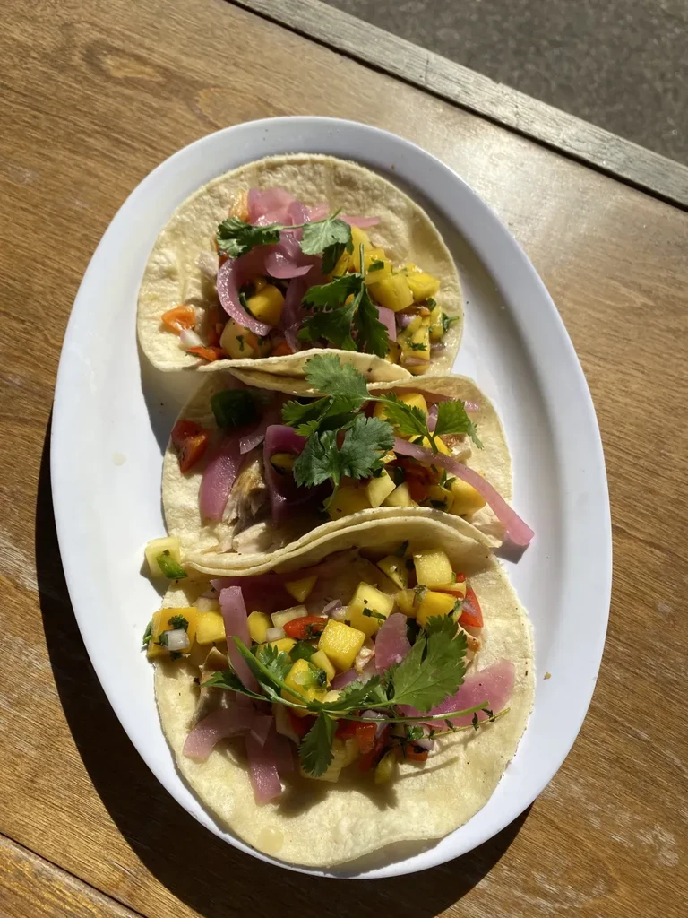 Three tacos with mango salsa, pickled red onions, and cilantro.