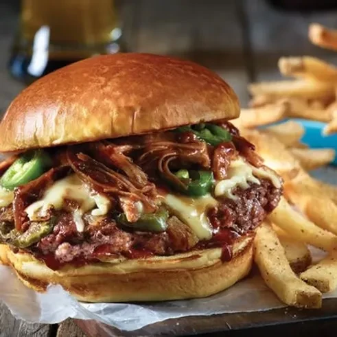 Gourmet burger with pulled pork, cheese, jalapeños, and French fries.