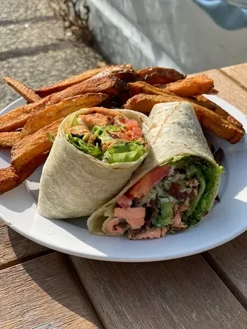 Plate of two wraps with salmon or chicken, and golden fries.