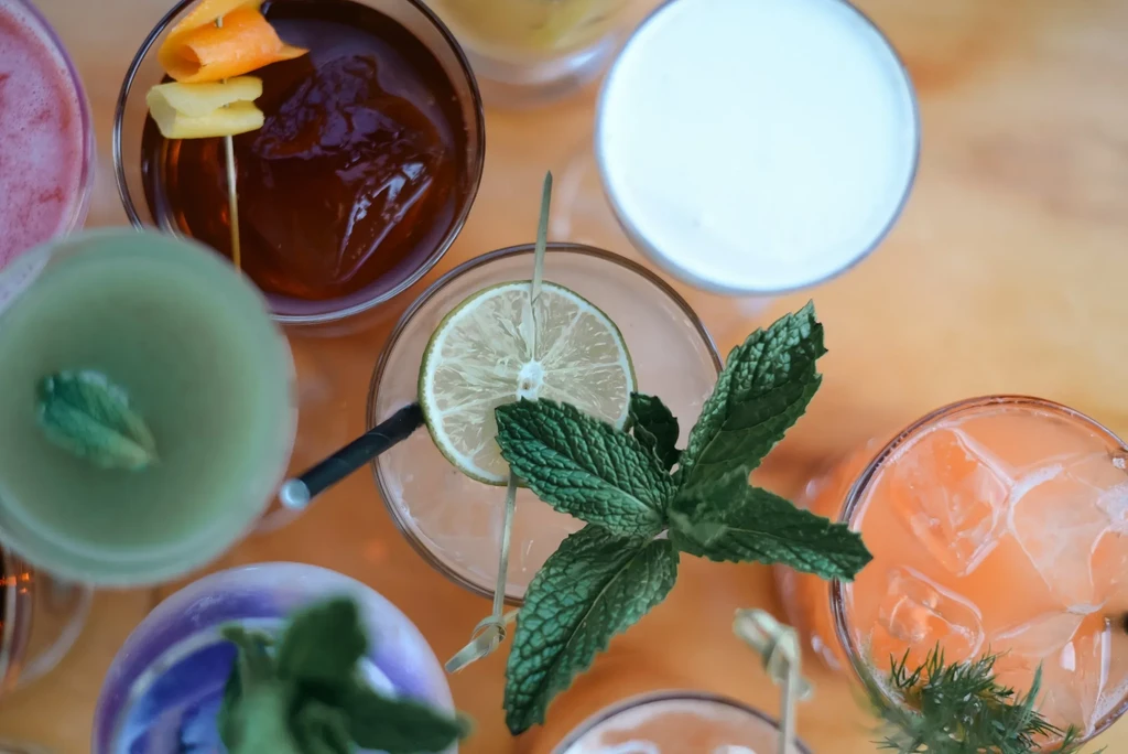Top-down view of colorful garnished drinks on a wooden table.