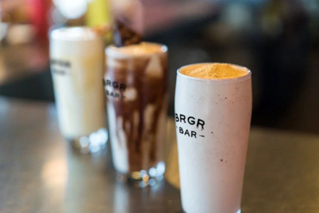 Three BRGR BAR milkshakes, one chocolate, one light with yellowish powder.