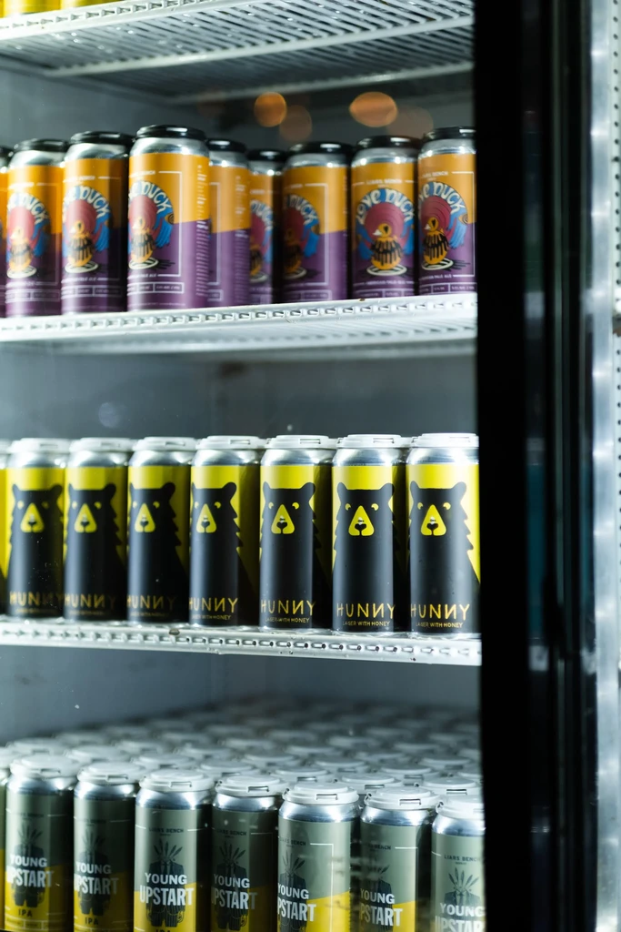 Open refrigerator with multiple shelves of colorful branded canned drinks.