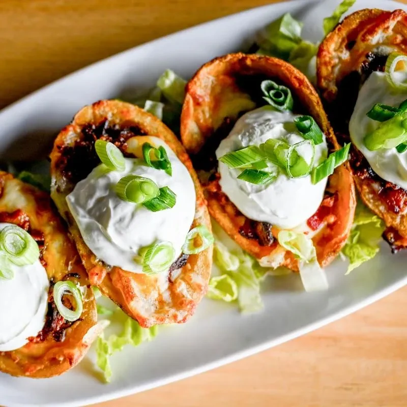 Four crispy potato skins topped with sour cream and green onions.
