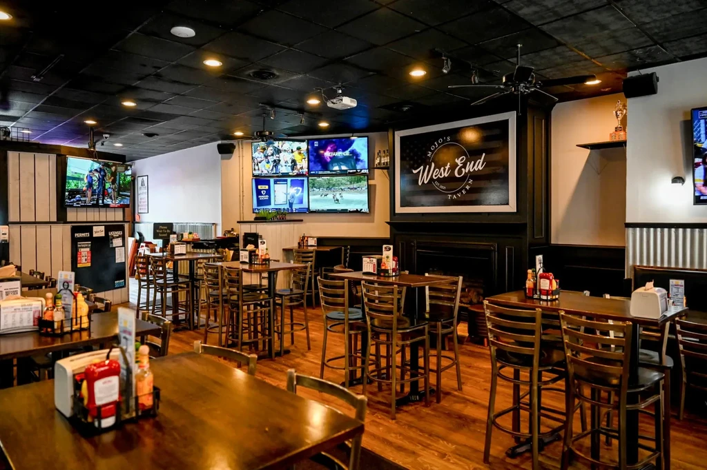 Empty Mojo's West End Tavern interior with high-top tables and TVs.