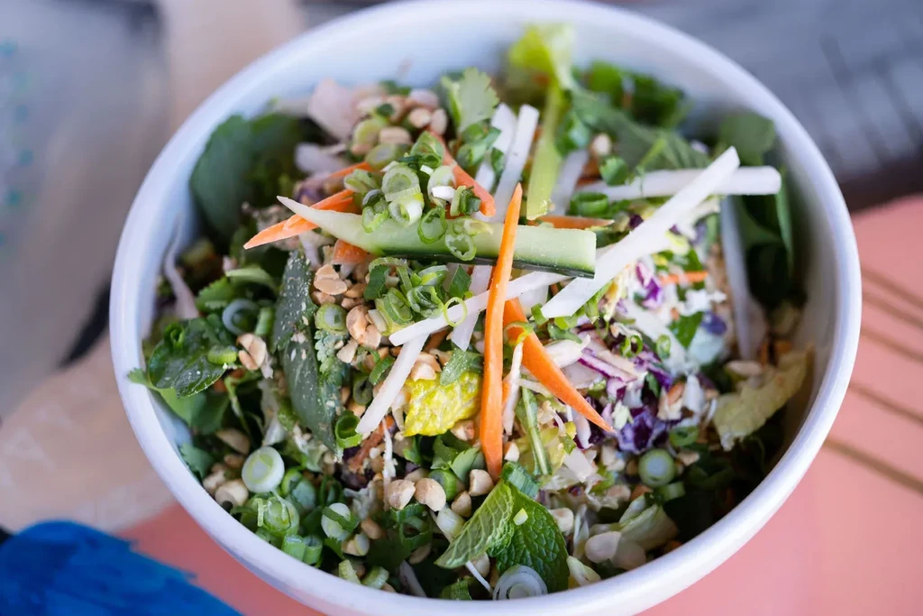 Vibrant salad bowl with fresh vegetables, peanuts, and citrus.